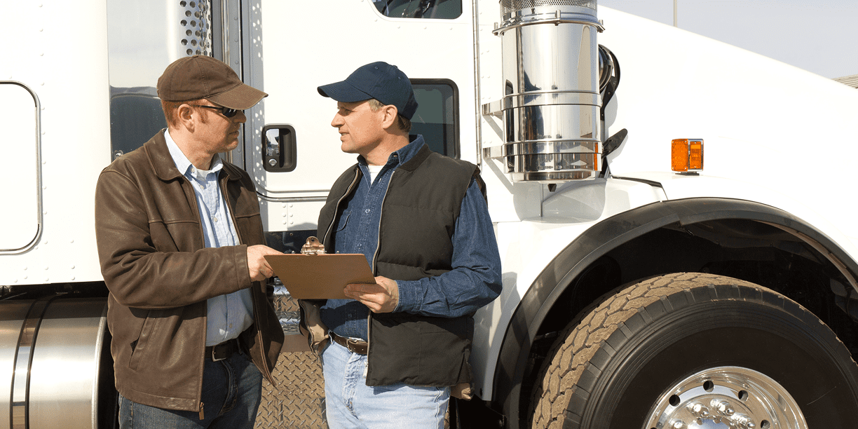 Two men discussing beside a large truck.