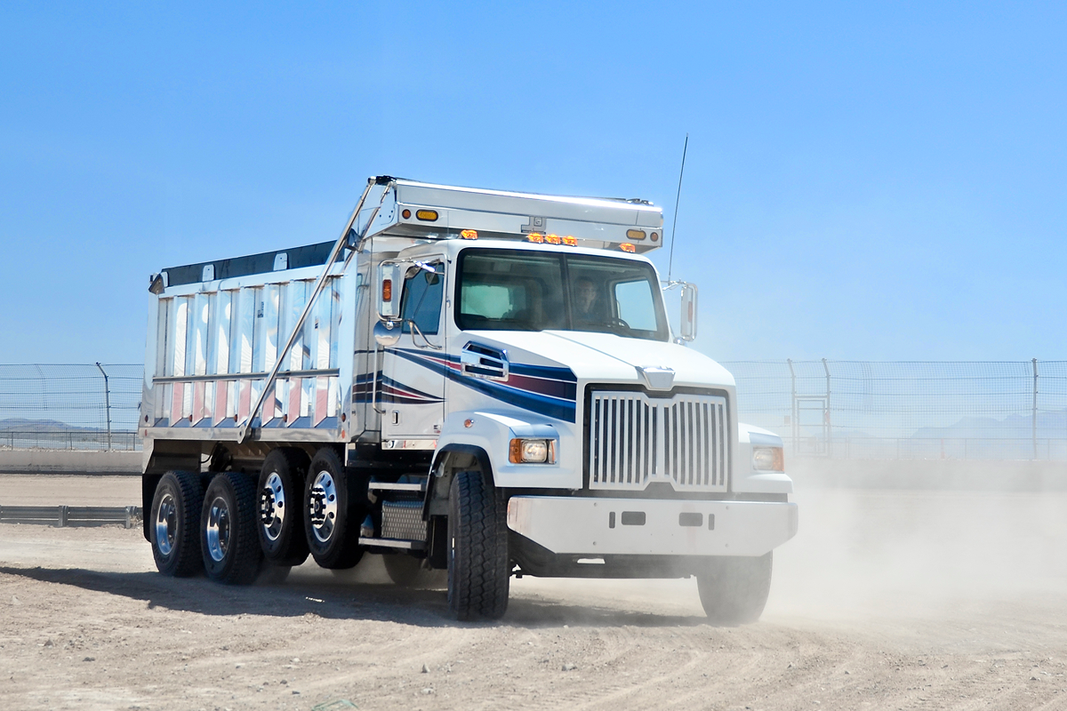 White dump truck driving on sandy terrain.